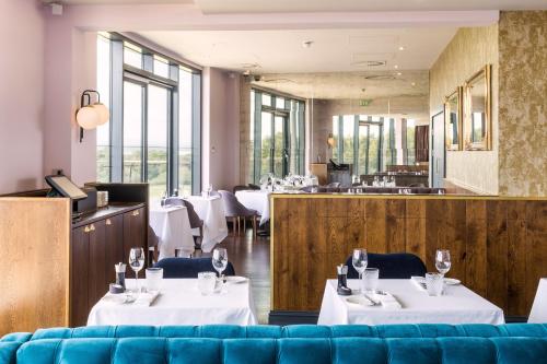 切斯特切斯特阿波得酒店的餐厅设有白色的桌椅和窗户。