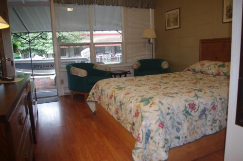 Lansdowne御千岛卡普里柯汽车旅馆的一间卧室配有一张床、两把椅子和一个窗户