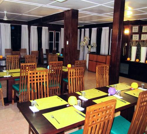 莫尔兹比港星霖小屋酒店的用餐室配有桌椅和黄色餐巾