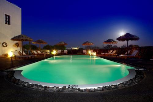 卡马利安娜传统公寓酒店的夜间游泳池,配有椅子和遮阳伞
