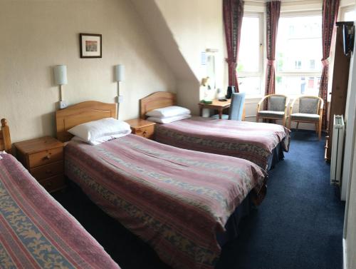阿伯丁Arkaig Guest House的酒店客房配有两张床和一张书桌
