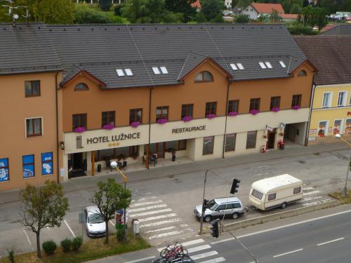 Planá nad Lužnicí卢日尼采酒店的街上的一座建筑,停车场有车辆停放