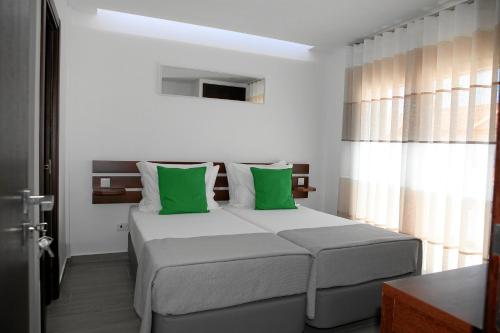 巴勒尔Baleal 4 Surf II的一间卧室配有一张带绿色枕头的大床