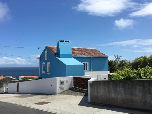 Porto JudeuCasa do Vizinho的蓝色和白色的房子,背景是大海