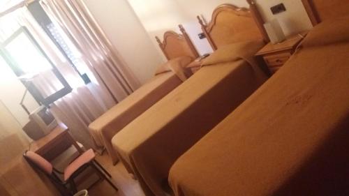 马斯萨内特德拉塞尔瓦Hostal Bonaterra的配有椅子和窗户的客房内的两张床