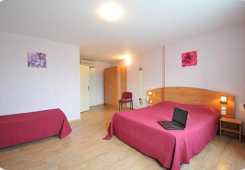 Witry-lès-Reims普里姆兰斯酒店的一间卧室配有粉红色的床,上面有笔记本电脑