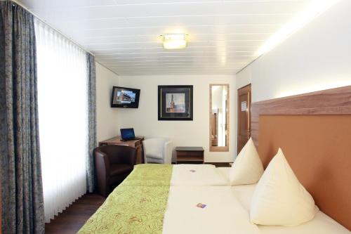 Ennigerloh胡博图斯酒店的配有一张床和一张书桌的酒店客房