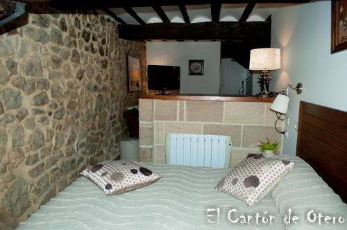 桑提亚纳德玛Estudios El Canton de Otero的一间卧室配有带枕头的床铺和石墙