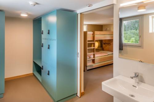 克莱恩 蒙塔纳克莱恩蒙塔纳瑞士青年旅舍的浴室设有蓝色橱柜、水槽和双层床。