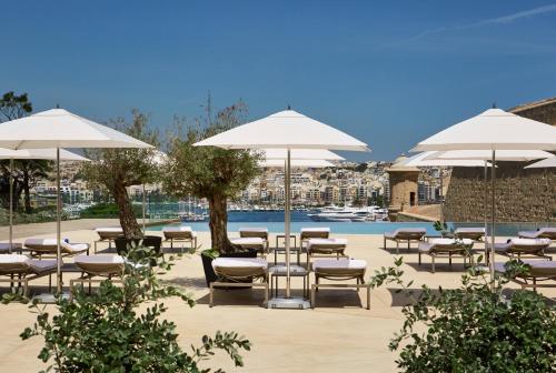 瓦莱塔The Phoenicia Malta的游泳池旁带椅子和遮阳伞的天井