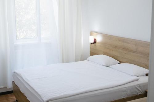 费尔干纳Sakura Inn的一张带两个枕头的白色床和窗户