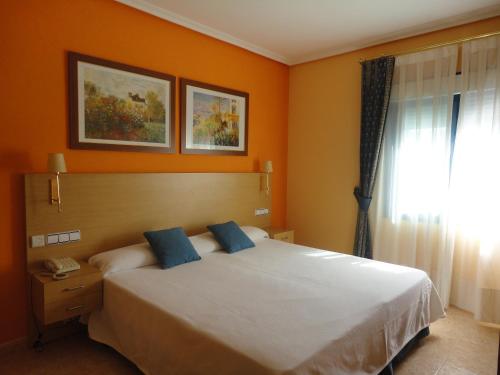 贝利利亚·德·圣安东米拉多尔酒店的一间卧室配有一张带橙色墙壁和窗户的床
