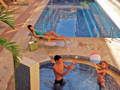 卡波布里奥Malibu Palace Hotel的男女在游泳池玩耍