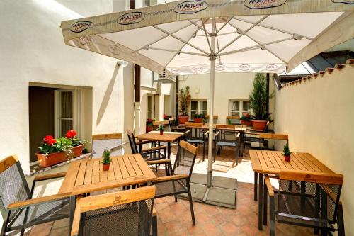 布拉格红狮大酒店的庭院配有木桌和椅子以及遮阳伞。