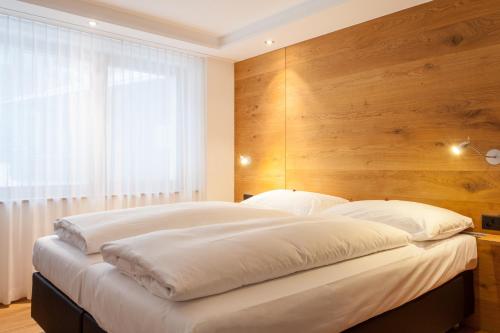 萨斯费精英高山小屋 - 公寓&住宿加早餐酒店的一间卧室设有一张带木墙的大床