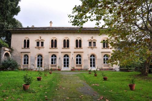 San-Martino-di-LotaCHÂTEAU CAGNINACCI B&B的一座白色的大建筑,在院子里种有植物