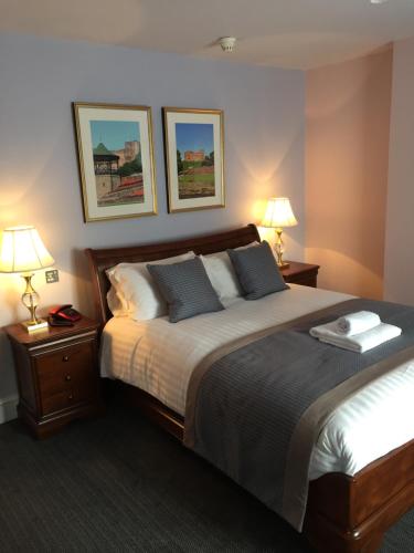 塔姆沃思城堡酒店的一间卧室配有一张大床、两盏灯和两张sidx单人床。