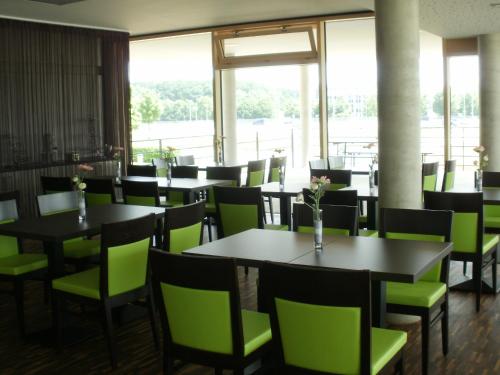 乌尔姆乌尔姆iQ酒店的用餐室配有桌子和绿色椅子