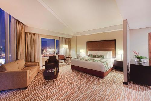 马尼拉Acacia Hotel Manila的大型酒店客房,配有床和沙发