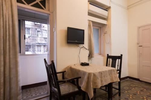 孟买戈拉巴住宿加早餐旅馆的一间设有桌子和墙上电视的用餐室