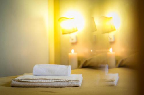摩德纳迪-坎皮格里奥波斯塔公寓式酒店的配有带2条毛巾和1把蜡烛的床的客房