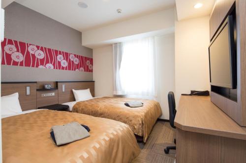 伊势市Sanco Inn Iseshi-Ekimae Shikinoyu的酒店客房设有两张床和一台平面电视。