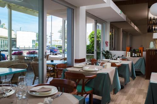 西尼加利亚Hotel Paradiso的餐厅设有桌椅和窗户。