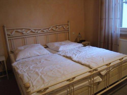 奥斯赛拜-屈隆斯博恩Kuehlungsborn-2-Zi-Ferienwohnung-LAGUNA-Residenz-am-Meer的卧室内的一张带白色床单和枕头的床