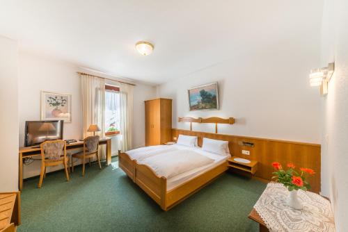 康斯坦茨高登斯蒂姆酒店的一间卧室配有一张床、一张书桌和一台电视