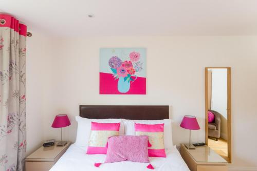 Aldringham萨福克诺迪什尔度假屋的一间卧室配有一张带粉红色枕头和镜子的床