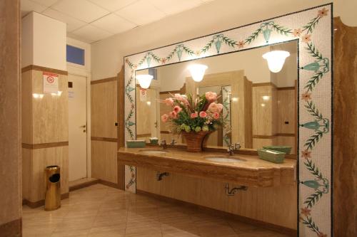 蒙特西尔瓦诺海滨长廊酒店的浴室设有水槽、镜子和鲜花