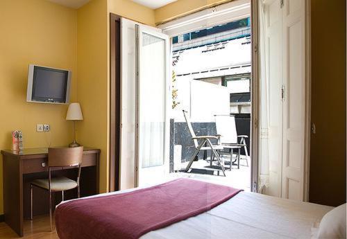 马德里阿斯托利亚旅馆的一间带一张床和一张书桌的卧室以及一个阳台