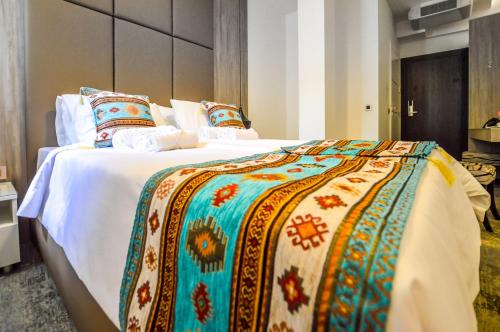 萨拉热窝萨拉热窝门赫里塔吉酒店的一张大床,配有色彩缤纷的毯子和枕头