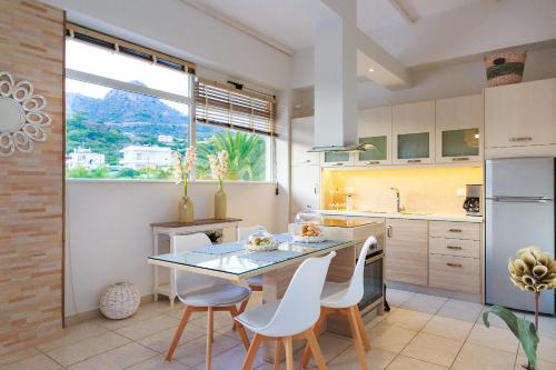 费马Chrissi Bay的厨房配有玻璃桌和白色椅子