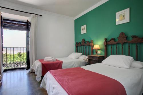 隆达卡萨罗恩德纳酒店的配有两张床的客房,设有绿色的墙壁和窗户
