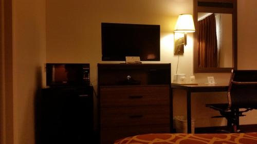 利柏提American Inn Of Liberal的酒店客房配有平面电视和带梳妆台的梳妆台。