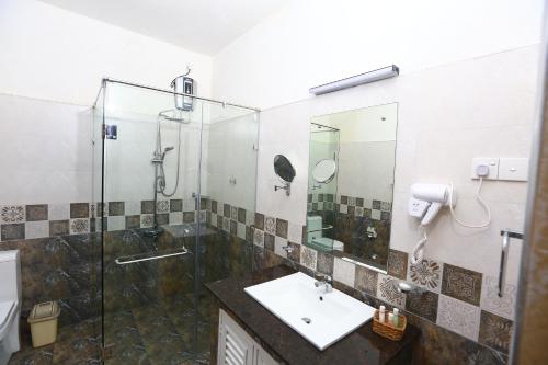 康提Peradeniya Rest House的一间带玻璃淋浴和水槽的浴室