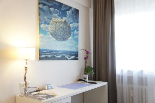 杜塞尔多夫维兰德商务酒店的配有一张桌子的房间,墙上挂着一幅画