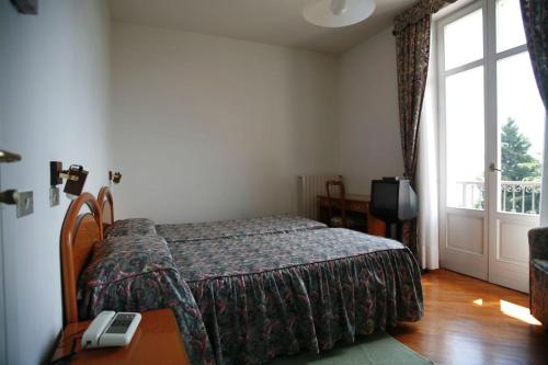 PremenoHotel Villa Rosy的一间卧室配有一张床、一张桌子和一个窗户。