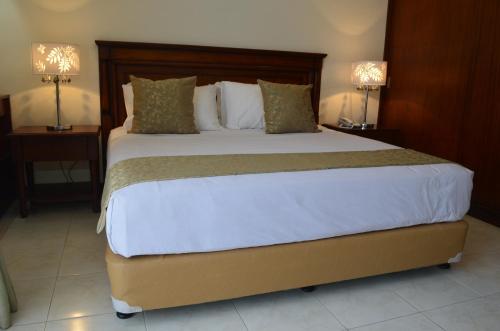 宿务格兰德伊莎贝拉公寓的一张大床,位于酒店带两盏灯的房间