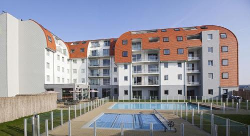 泽布吕赫Holiday Suites Zeebrugge的公寓大楼前方设有游泳池