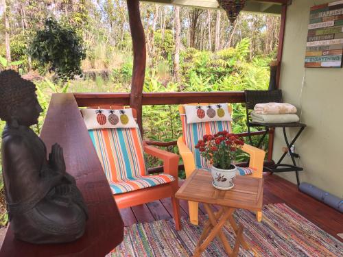 沃尔卡诺Volcano Eco Cabin & Eco Lodge的门廊配有两把椅子和一张花瓶桌子