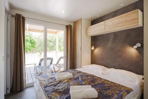 波雷奇Mobile Homes - FKK Nudist Camping Solaris的一间带大床的卧室和一个阳台