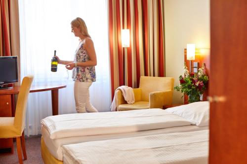 慕尼黑协和酒店的一位站在酒店房间并带一瓶葡萄酒的女士