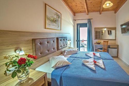 古瓦伊蓝色爱琴海套房公寓式酒店的一间卧室配有蓝色的床,上面有红色的鲜花