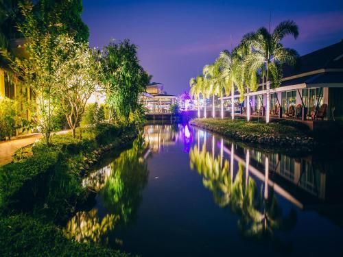 北碧Good Times Resort Kanchanaburi的一条棕榈树和建筑物的河