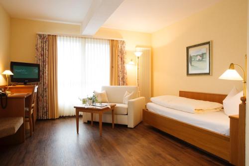 伊勒蒂森道韦勒之家酒店及餐厅的酒店客房配有一张床、一把椅子和一台电视。