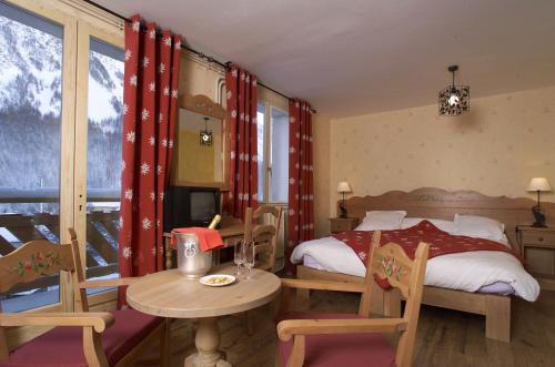 Villar-dʼArène古币酒店的卧室配有一张床和一张桌子及椅子