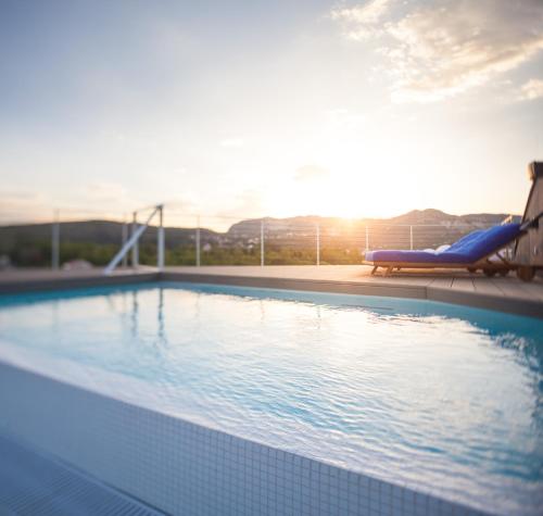 米利尼One Suite Hotel的一个带躺椅的游泳池,享有日落美景
