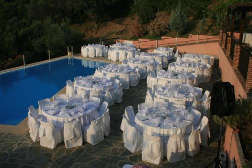 LímniVateri的一组桌子,旁边是游泳池,配有白色椅子